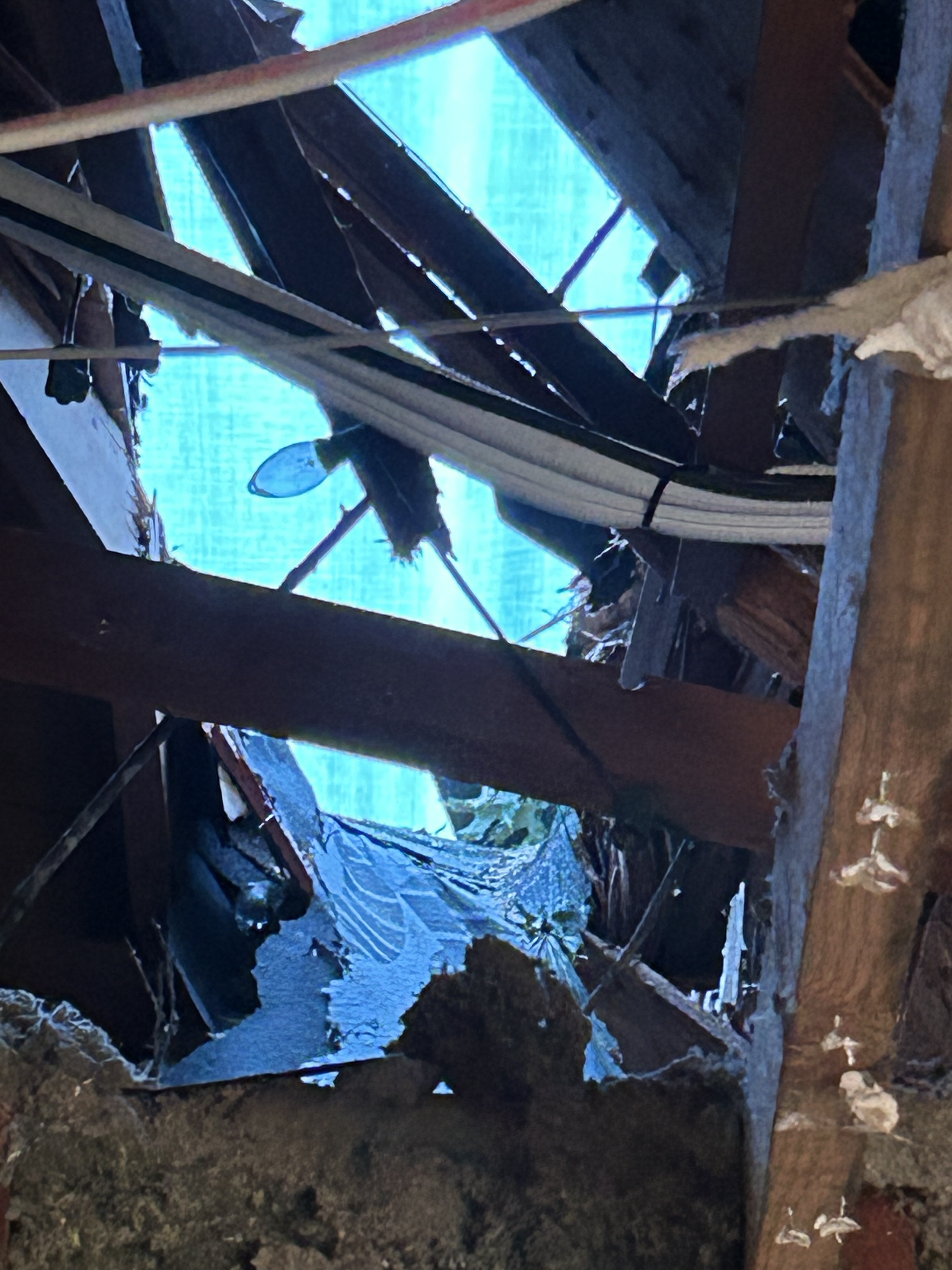 Extreme angle view of a ceiling with debris and wires exposed.